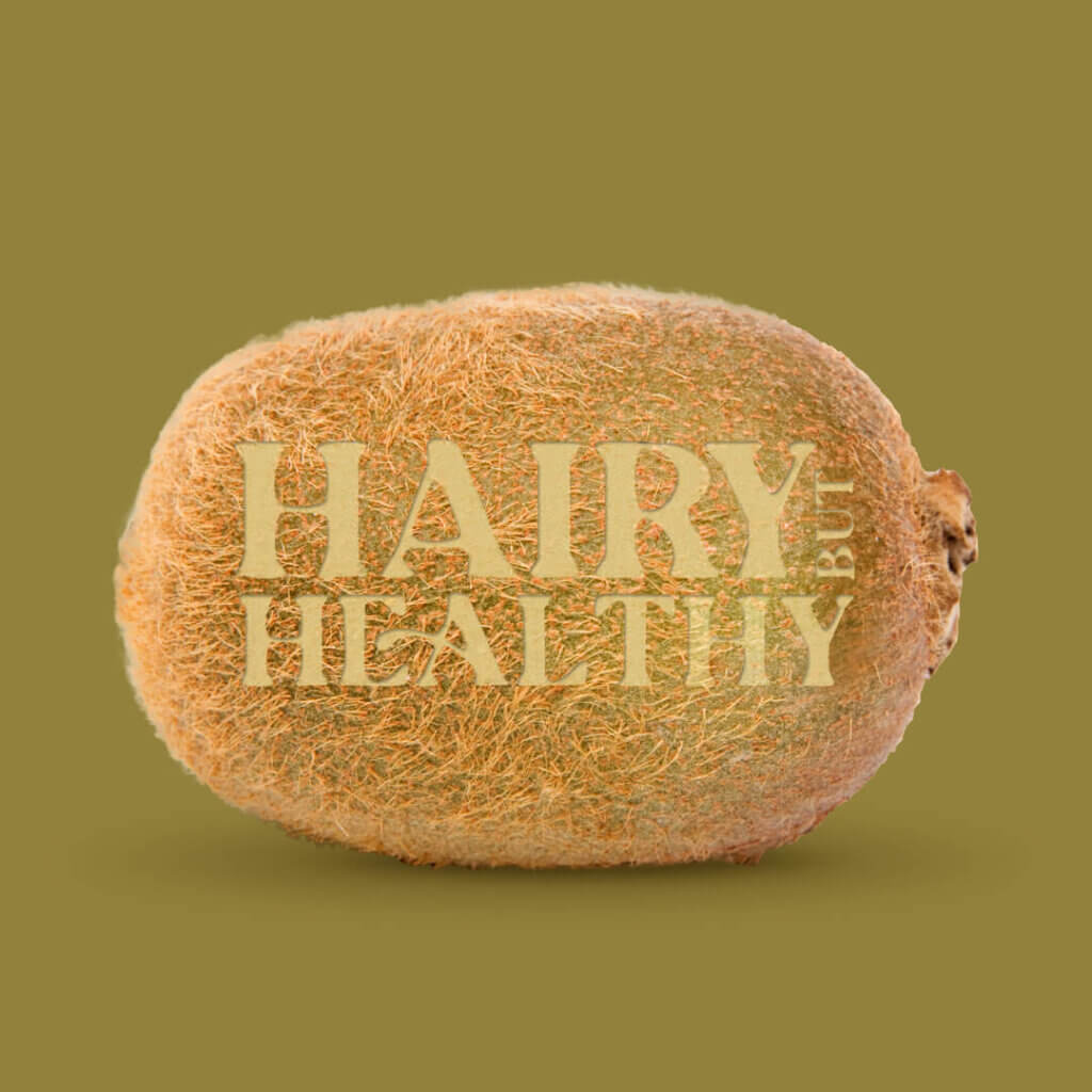 Image depicts a Kiwi laid on it's side, with text lasered into its skin. The text reads Hairy but healthy.